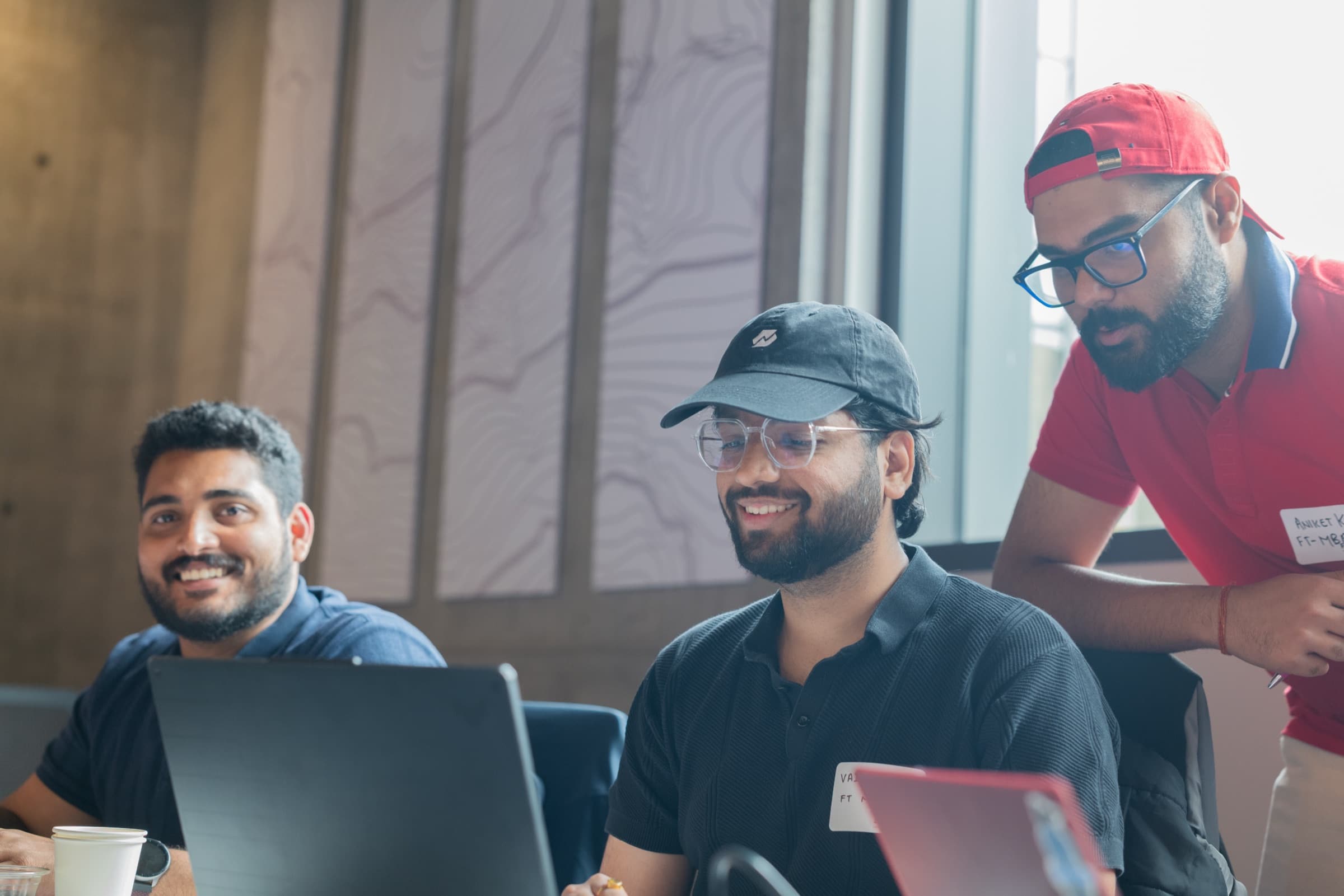 Hackathon participants smiling and discussing a laptop screen.