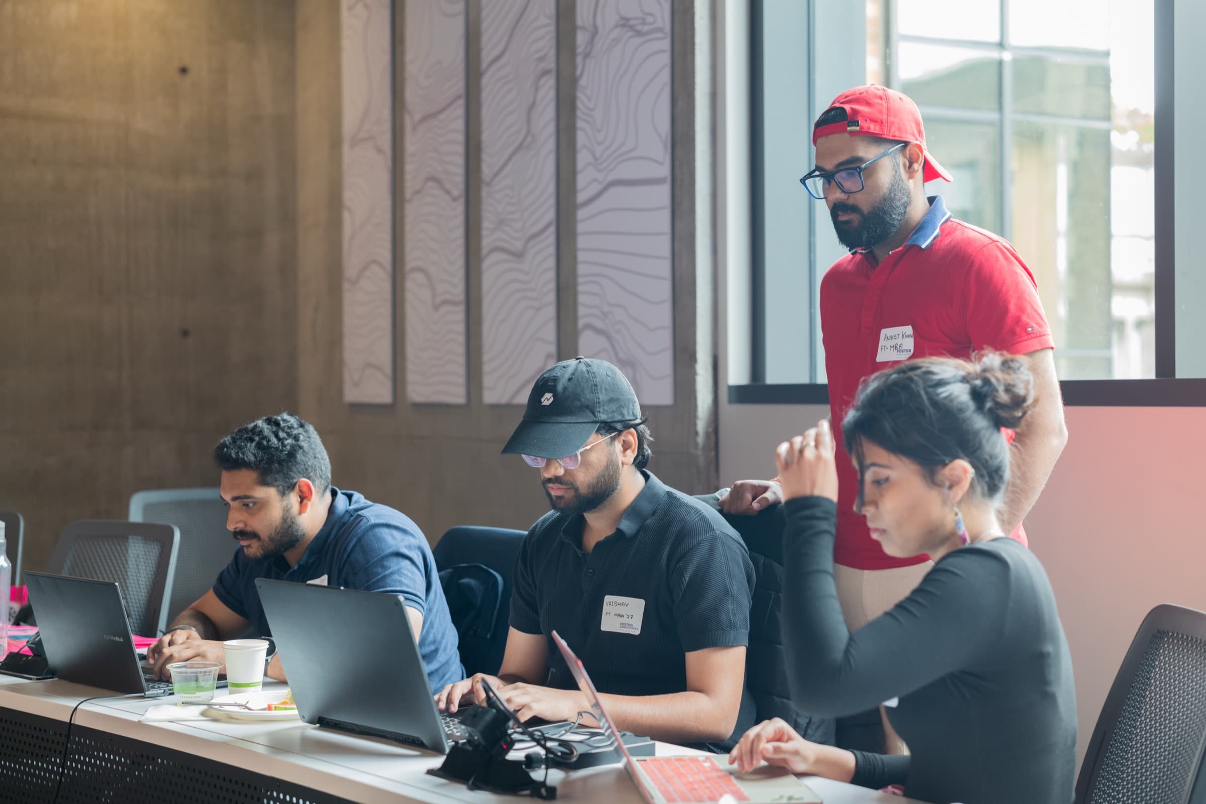 A group of hackathon participants working together around laptops.