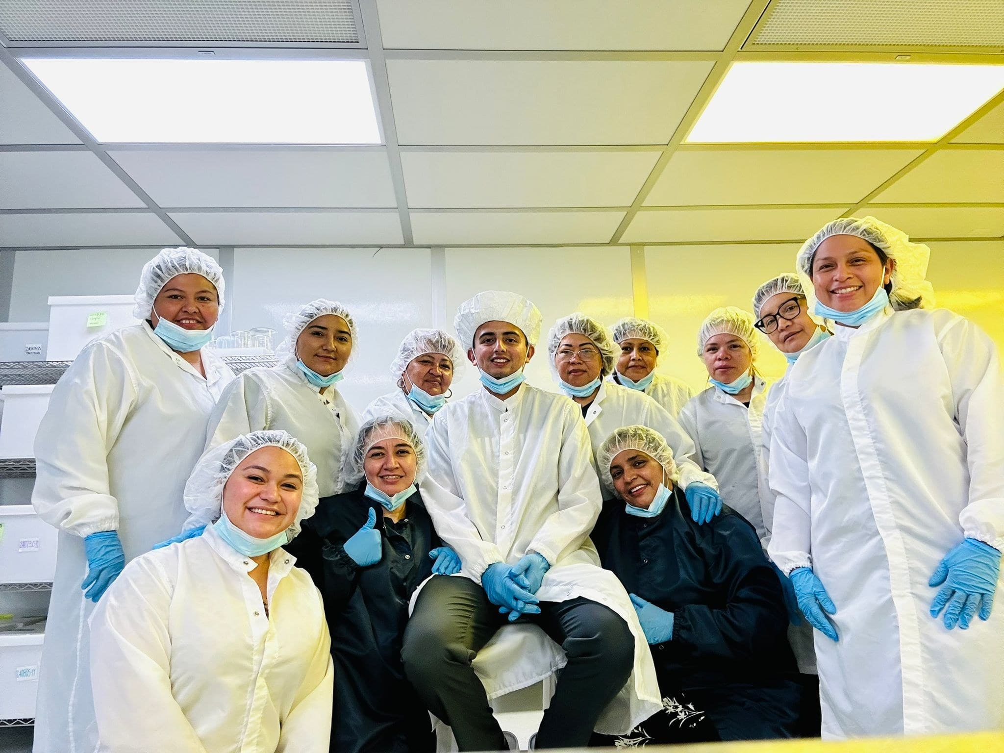 Empire colleagues posing together in lab coats and hair coverings in a production room.