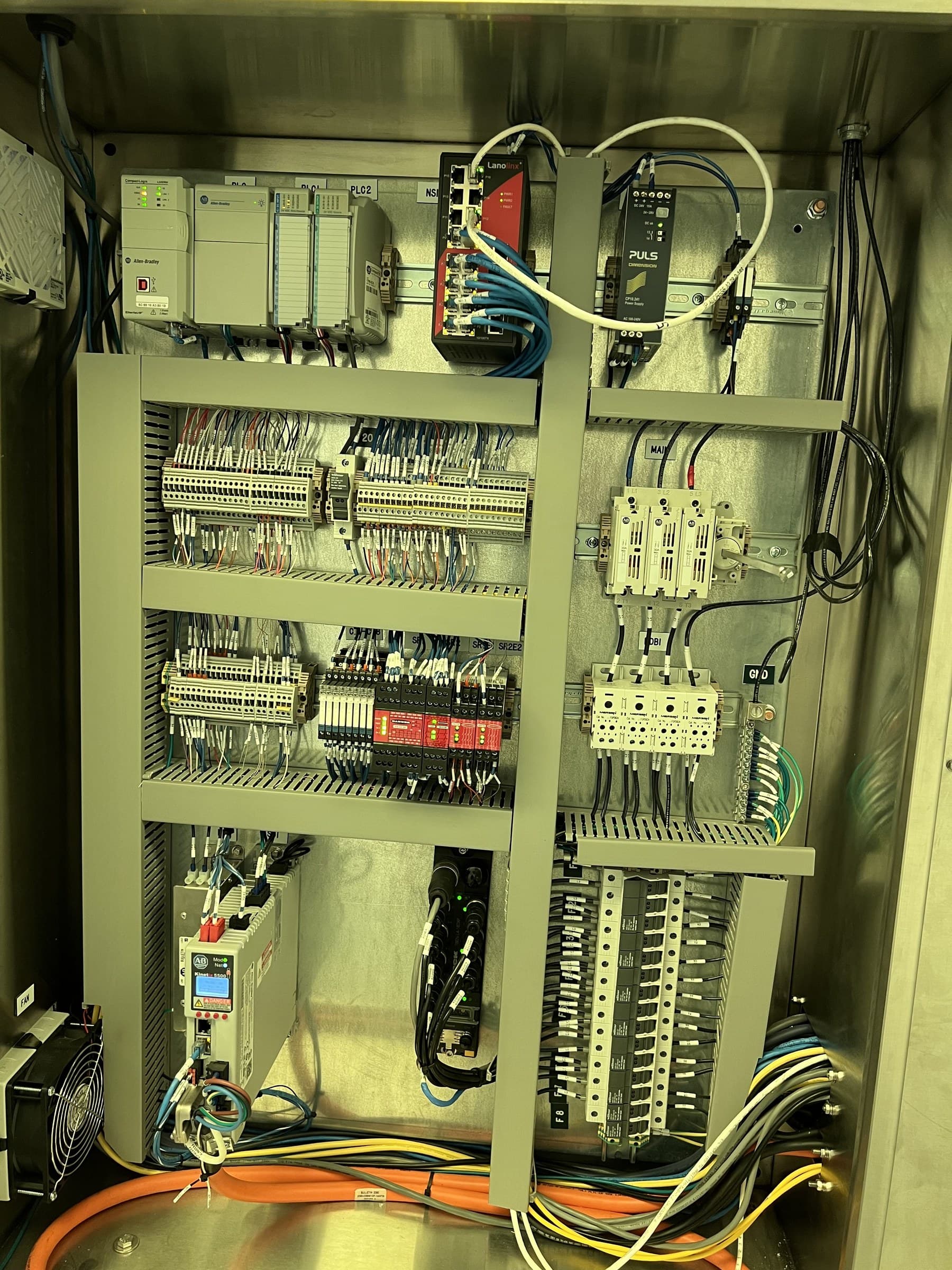 Open industrial control cabinet with controllers, network connections, and organized wiring.