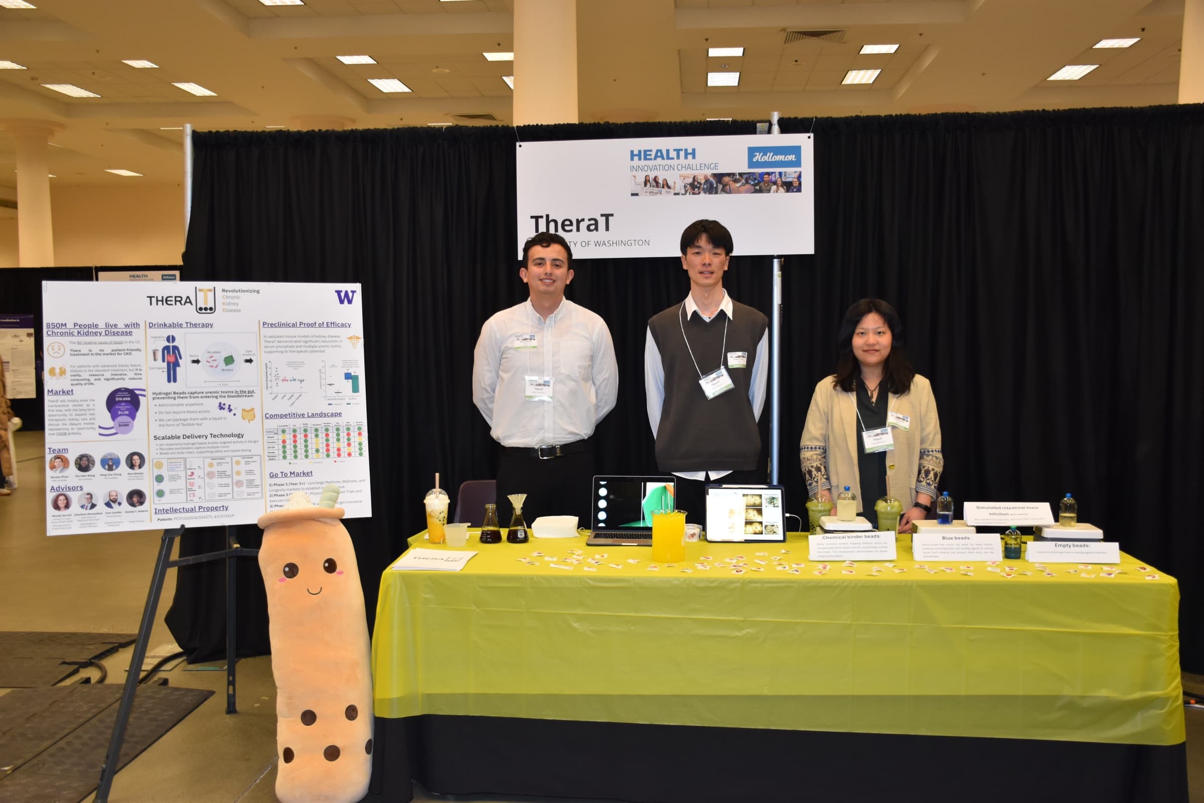 Three TheraT team members behind their Health Innovation Challenge exhibit table.