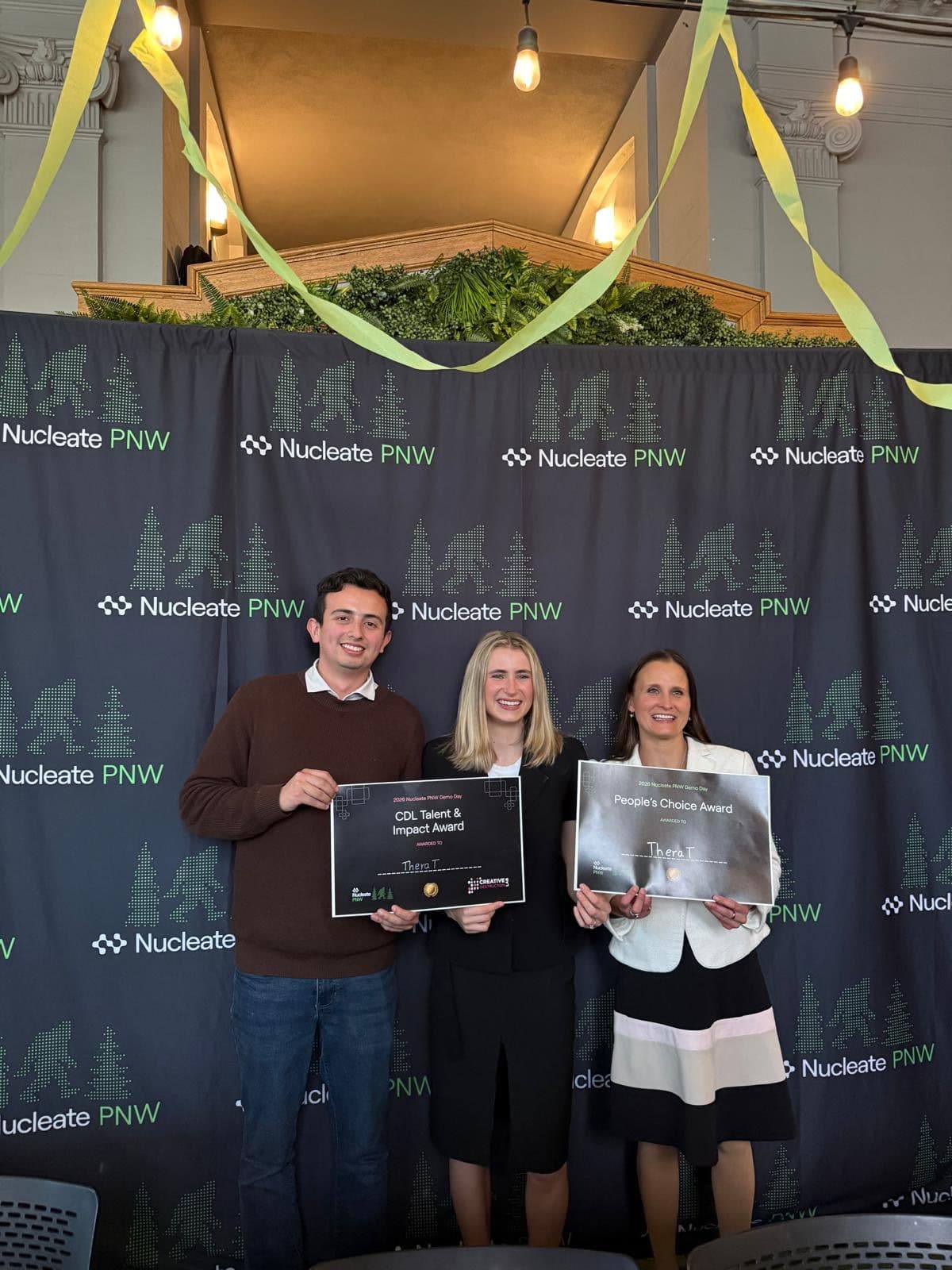TheraT team holding award certificates at Nucleate PNW Demo Day with Mari Winkler, principal investigator, and Paige DeOra, a recent bioengineering graduate and clinical coordinator at Rainier Clinical Research Center.