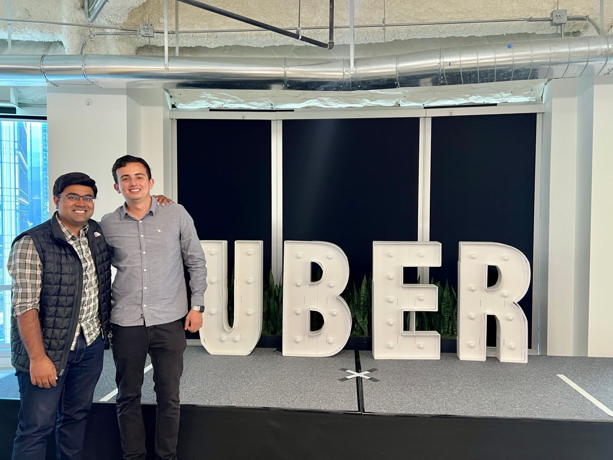 Nicolas and his manager standing beside large lit-up UBER letters.