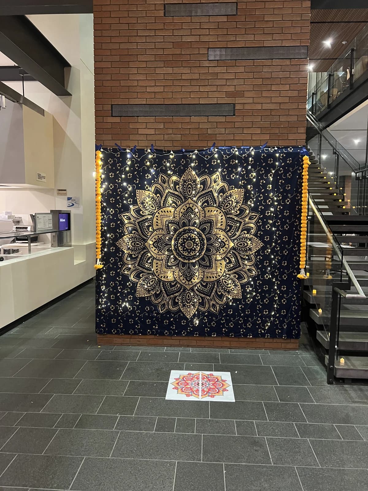 A patterned backdrop, lights, flowers, and rangoli decoration prepared for Diwali.