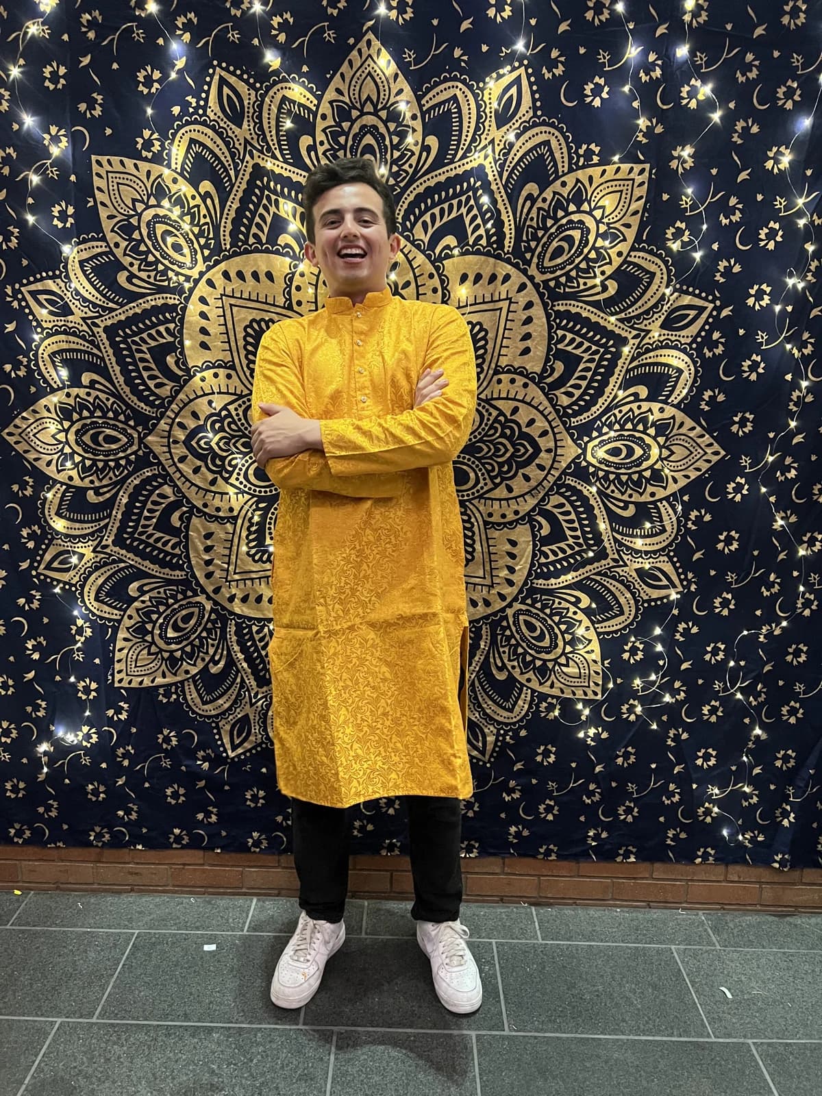 Nicolas wearing a yellow kurta in front of the Diwali backdrop.