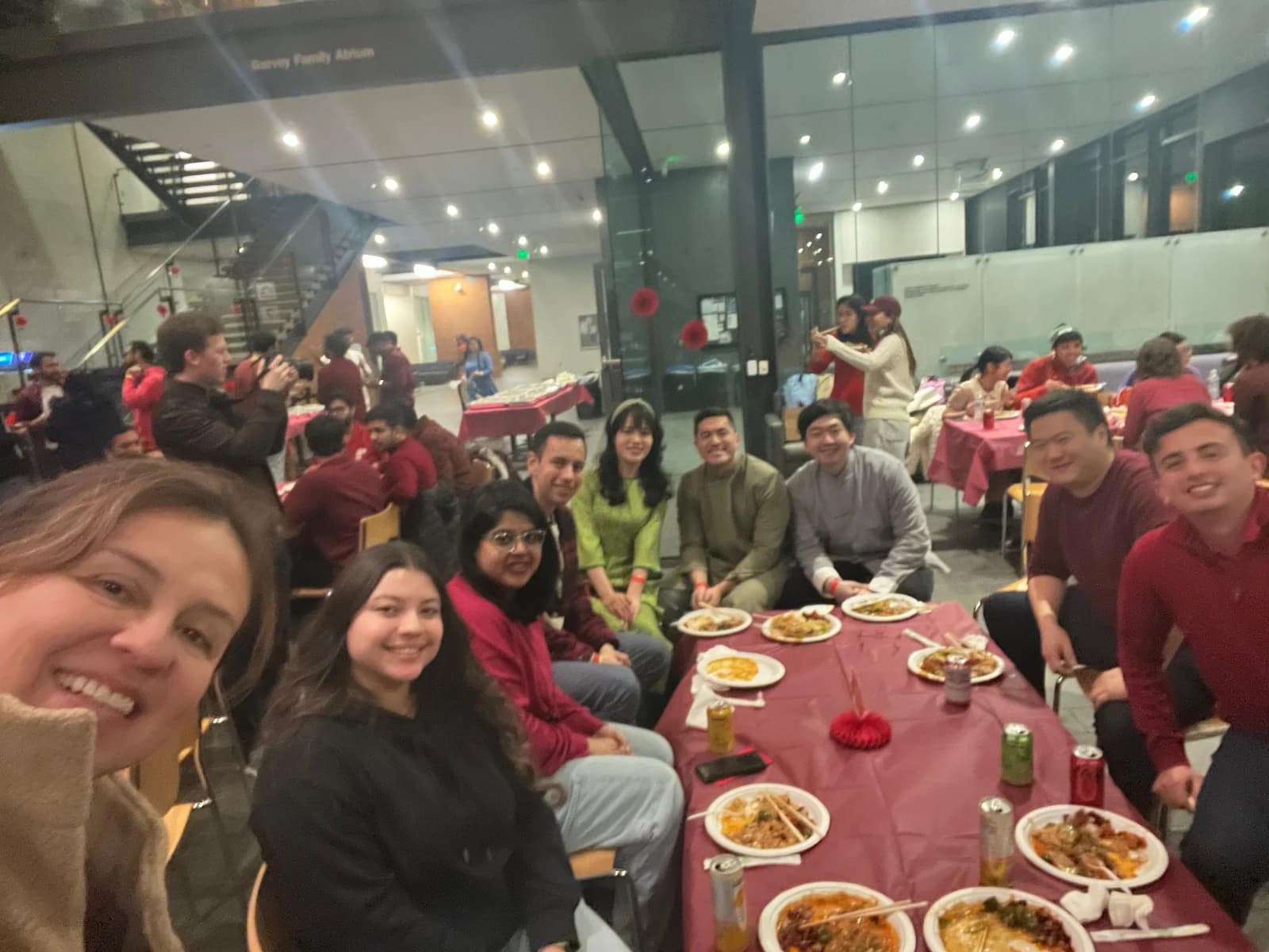 Classmates gathered around a table with food and red decorations during Chinese New Year.